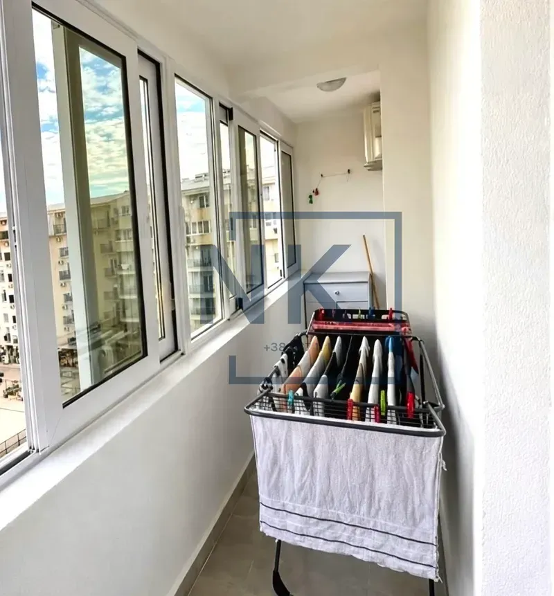 Zastakljeni balkon sa sušilicom za veš i velikim prozorima.