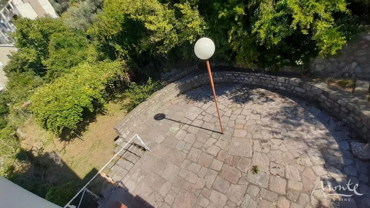 Paved terrace with a post lamp surrounded by greenery.