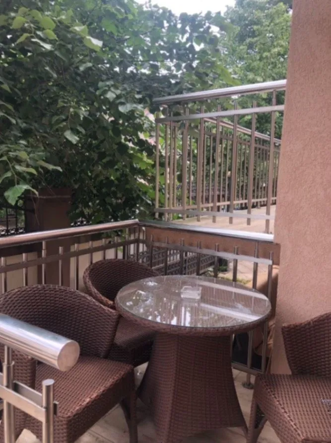 A balcony with wicker furniture and a round glass table.