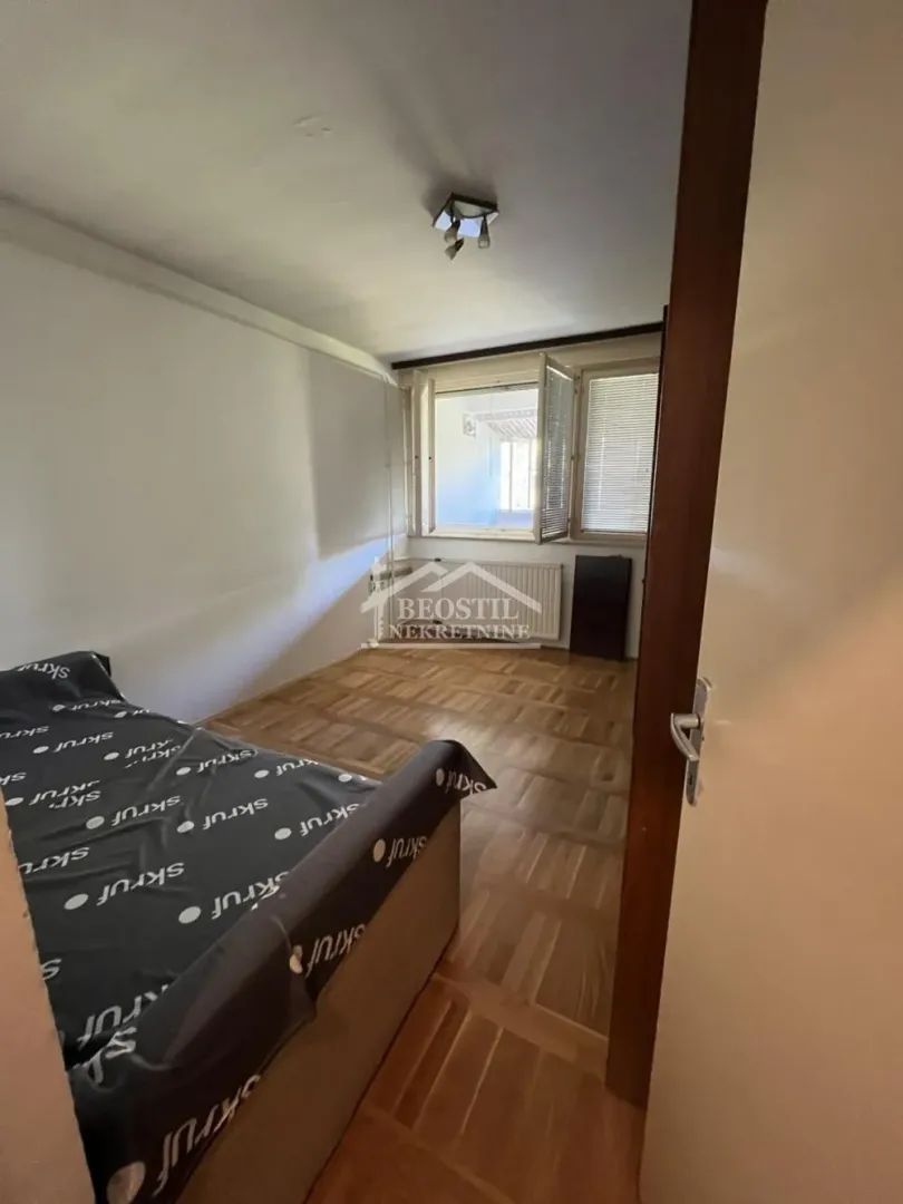 Smaller bedroom with a bed and wooden parquet flooring.