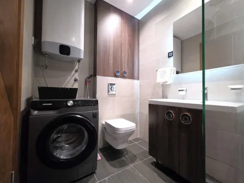 Modernly equipped bathroom with a washing machine, walk-in shower, and sanitary fixtures. - image 11