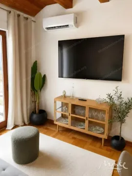Part of the living room with a TV, wooden sideboard, air conditioning unit, and balcony door. - image 4