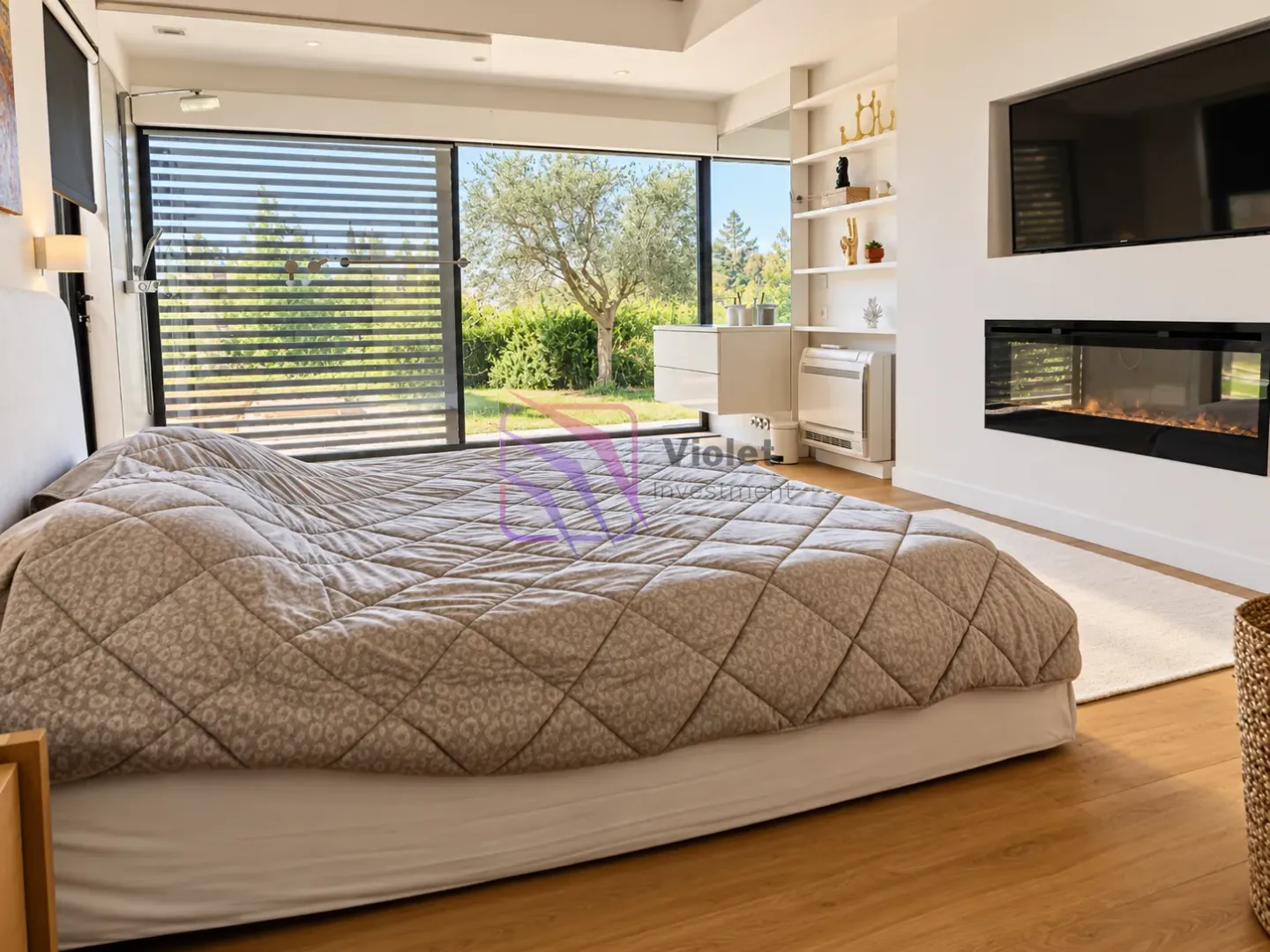 Modern bedroom with a double bed, fireplace, and large window overlooking greenery.