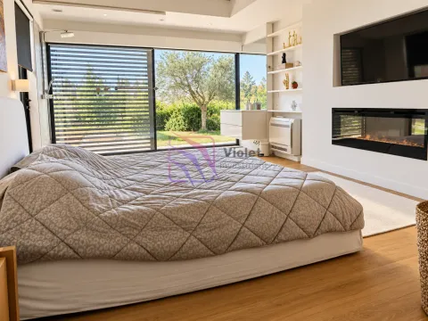 Modern bedroom with a double bed, fireplace, and large window overlooking greenery. - image 18