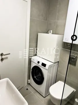View of the bathroom with a washing machine and toilet. - image 6