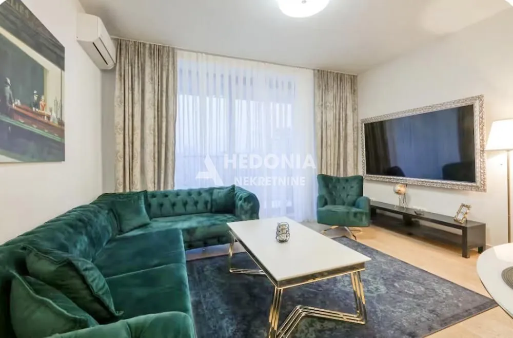 Living room with a comfortable green sectional sofa, large TV, and a dining table.