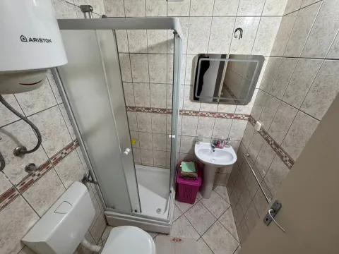 Smaller bathroom with a shower cabin, sink, toilet, and water heater. - image 7
