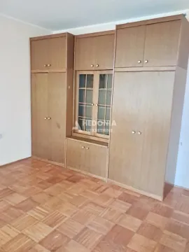 Spavaća soba sa velikim drvenim ormanom i parketom na podu. - image 3