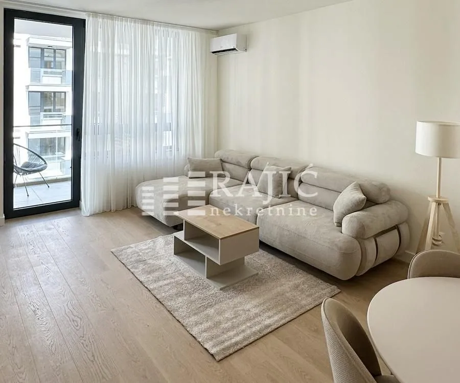 Bright living room with a sofa, dining table, and access to the terrace.