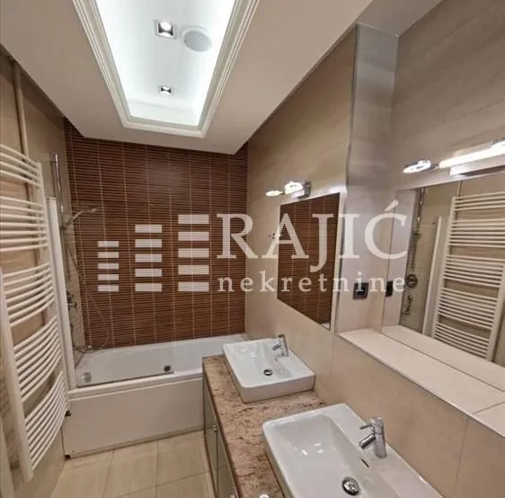 Modernly equipped bathroom with two washbasins and a bathtub.