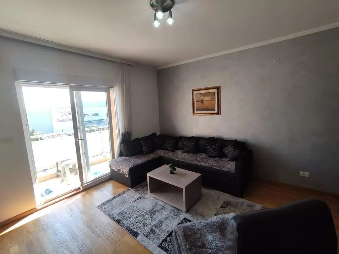 Dnevna soba sa ugaonom garniturom i izlazom na balkon.