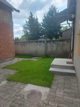 Dvorište kuće sa travnjakom i popločanim delom. - image 18