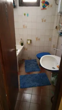 Jednostavno kupatilo sa kadom, umivaonikom i plavim prostirkama. - image 4