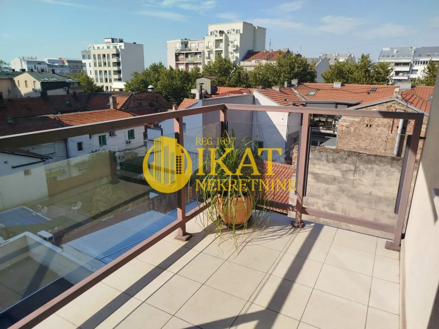Pogled sa popločane terase na gradske krovove i okolne zgrade.