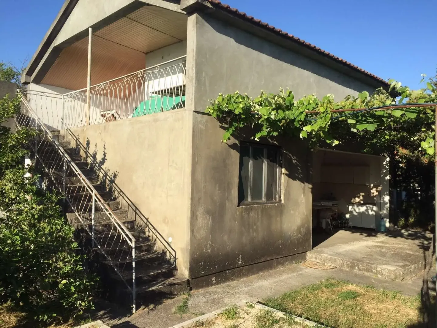 Exterior of a two-story house with outdoor stairs and a terrace.