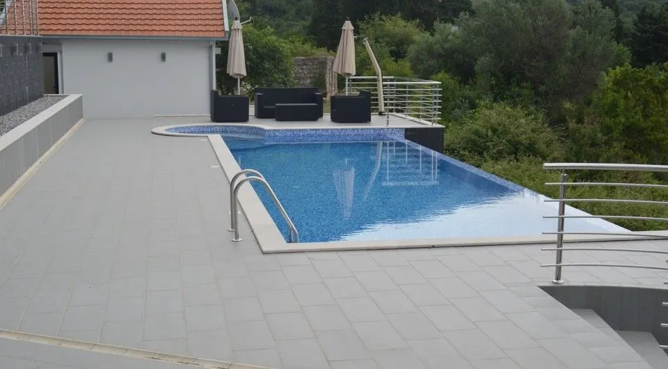 Bazen sa popločanom terasom i garniturom za sjedenje u dvorištu kuće.