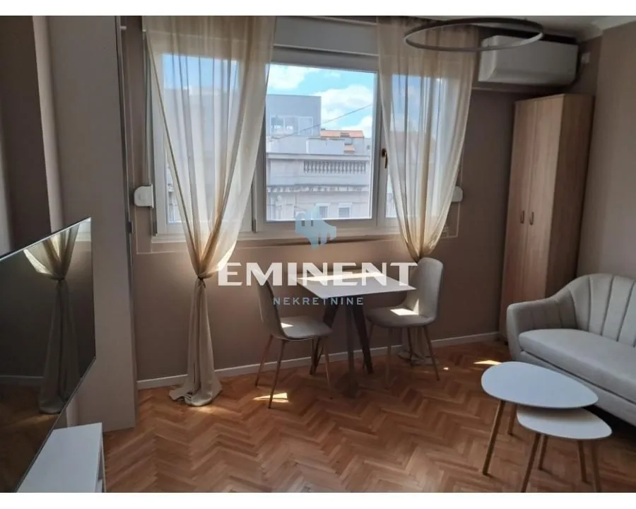 Small living room with a sofa, dining table, and a window.