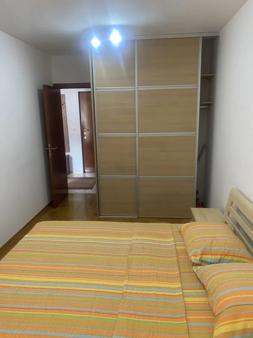 A bedroom featuring a large built-in wardrobe and a bed with colorful sheets.