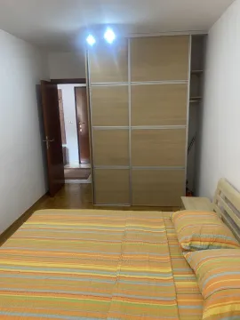 A bedroom featuring a large built-in wardrobe and a bed with colorful sheets. - image 10