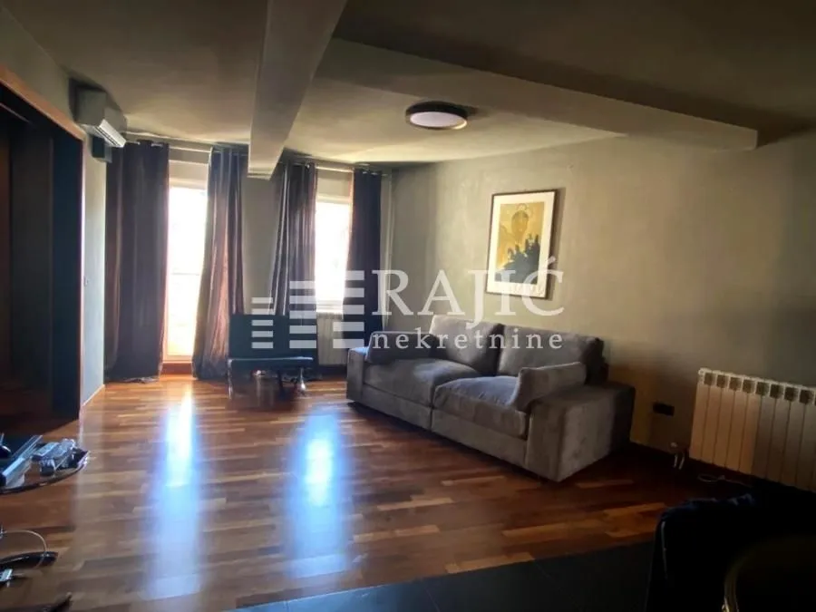 Living room with sofa, dark walls and wooden floor.