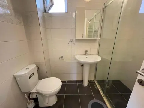Bathroom equipped with a toilet, washbasin, and shower cabin. - image 8