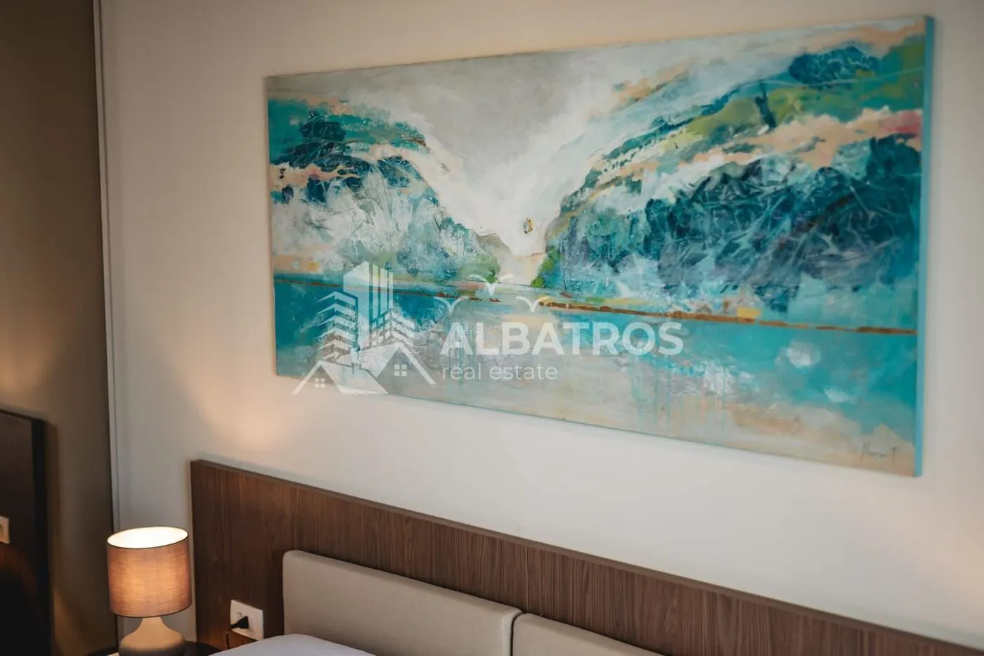 Part of the bedroom with a headboard and an art painting on the wall.