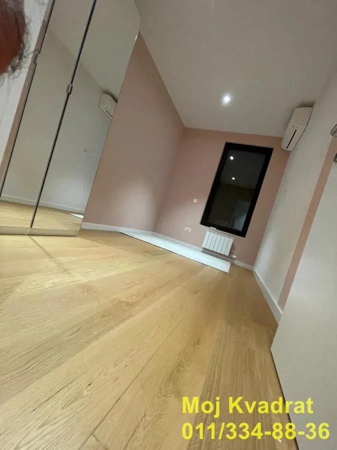 Small room with wooden flooring, mirrored wardrobe, and air conditioning.