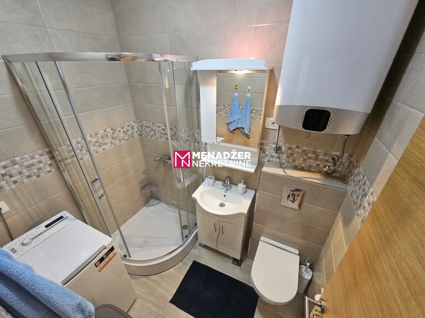 Manje kupatilo sa tuš kabinom, umivaonikom i wc šoljom.