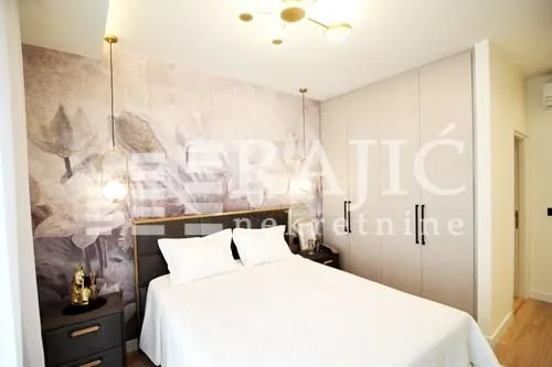Modern bedroom with a double bed, built-in wardrobe, and wallpaper on the wall.
