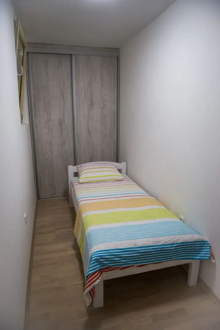Manja spavaća soba sa krevetom i ugradnim plakarom.