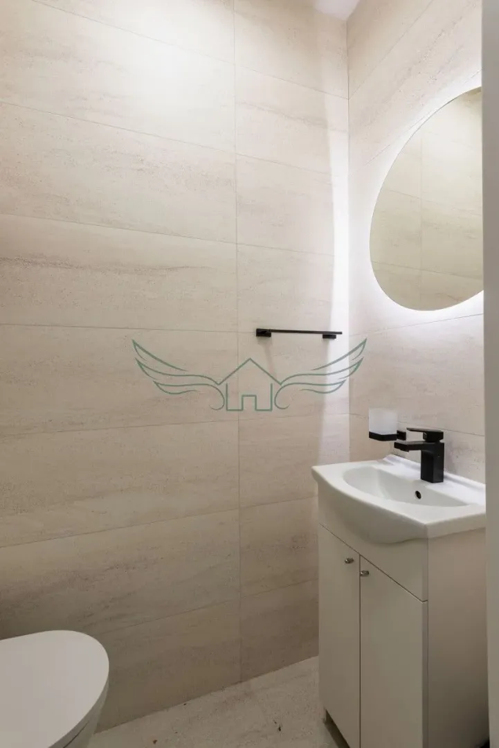 Moderno opremljeno kupatilo sa umivaonikom, ogledalom i WC šoljom.