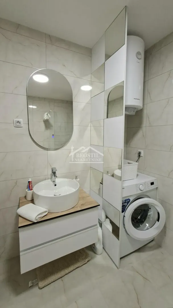 Modernly equipped bathroom with a washbasin, mirror, and washing machine.
