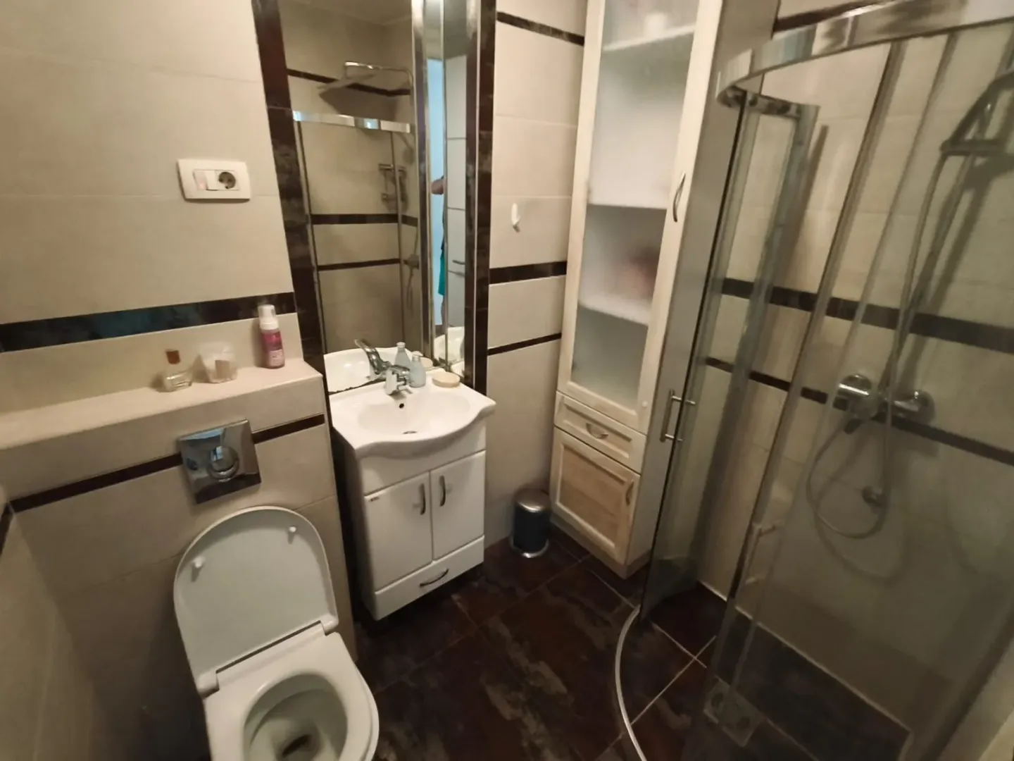 Compact bathroom with a shower cabin, washbasin, and toilet.