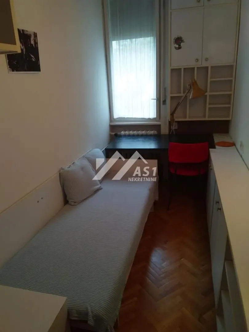 Small bedroom with a bed, desk, and a window.