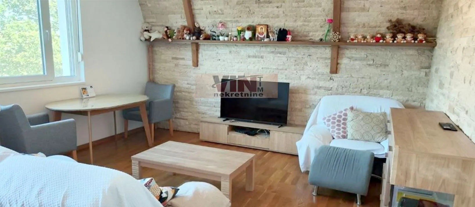 Dnevna soba sa garniturom, televizorom i trpezarijskim stolom.