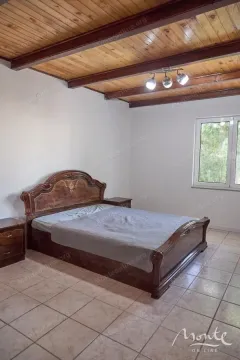 Spavaća soba sa bračnim krevetom i drvenim plafonom. - image 4