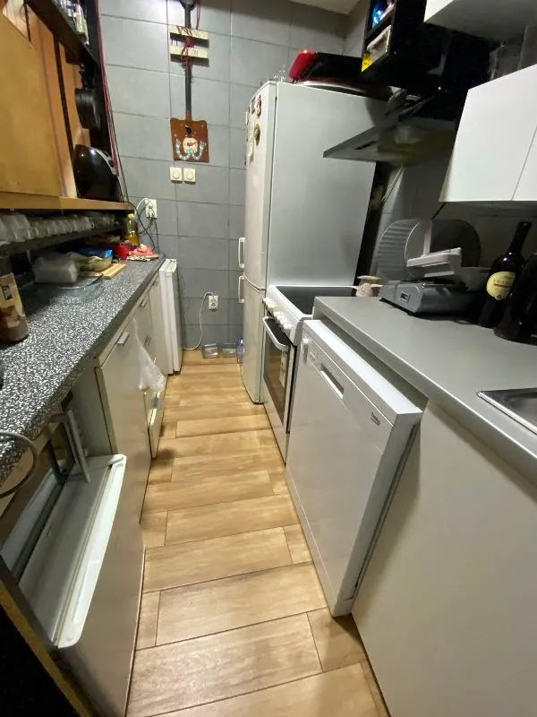 Small equipped kitchen with white goods and wooden elements.
