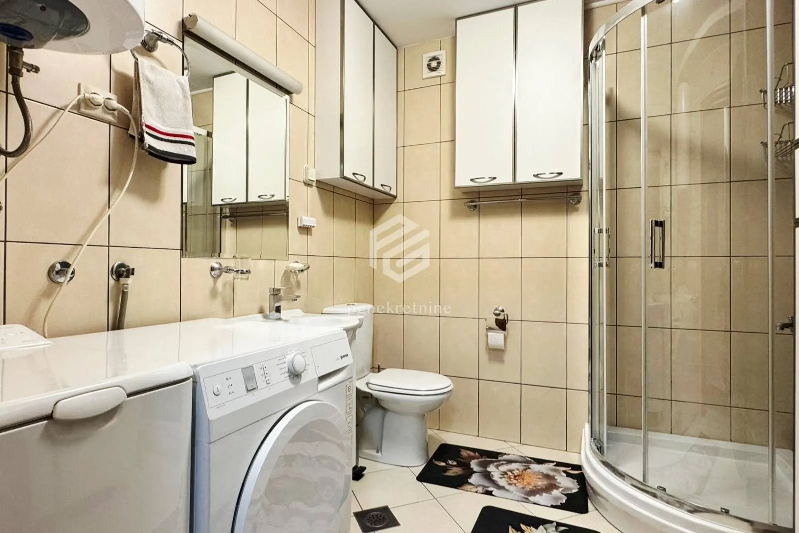 Bathroom equipped with a shower cabin, washbasin, toilet, and washing machine.
