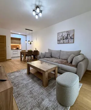 Living room with a sofa, coffee table and dining area in the background. - image 2
