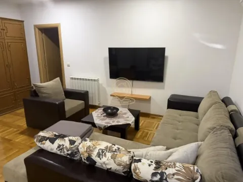 Nameštena dnevna soba sa garniturom, foteljom i televizorom na zidu. - image 2