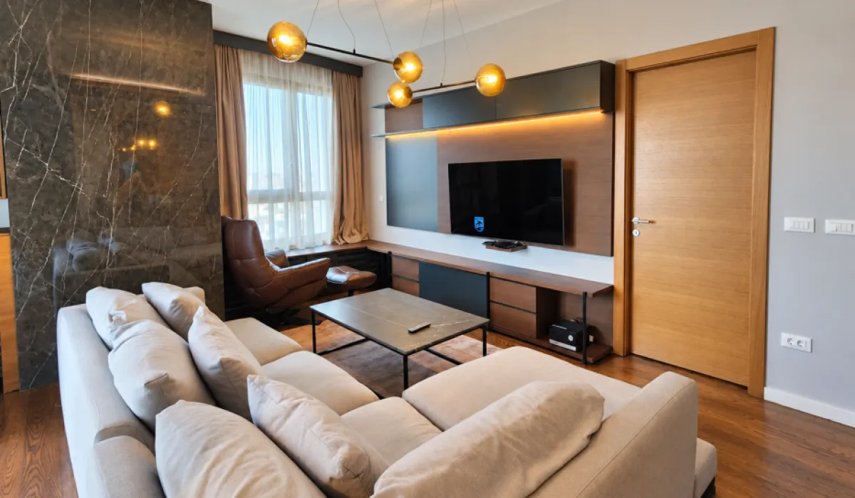 Modern living room with a sofa, TV, and dining area.