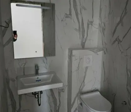 Kupatilo obloženo keramičkim pločicama sa umivaonikom i toaletom. - image 7