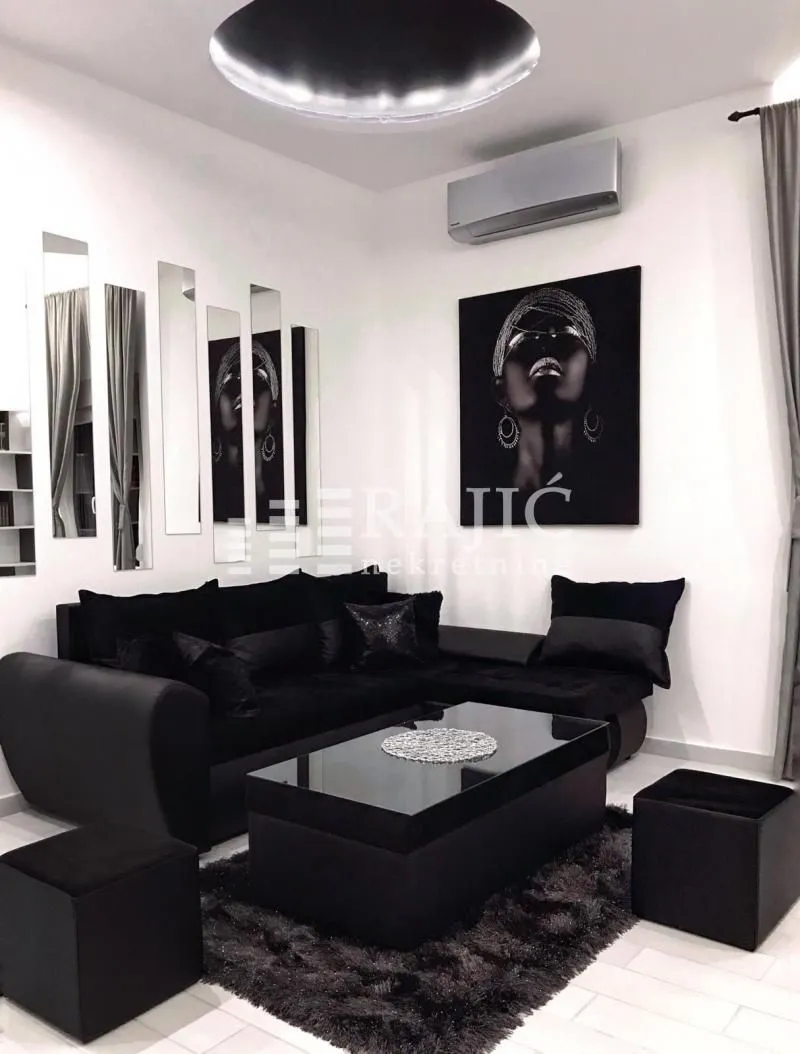 Modern living room with black furniture and wall art.