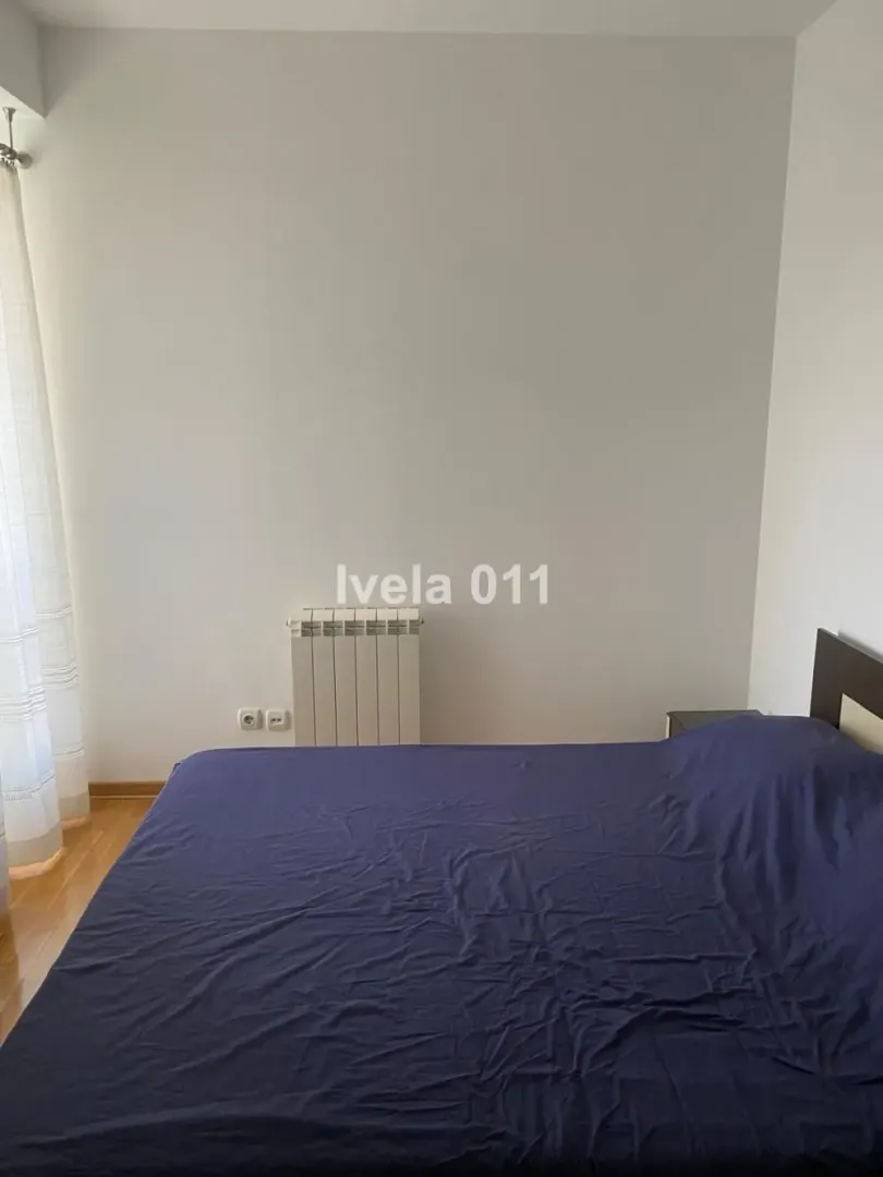 Spavaća soba sa bračnim krevetom i radijatorom.