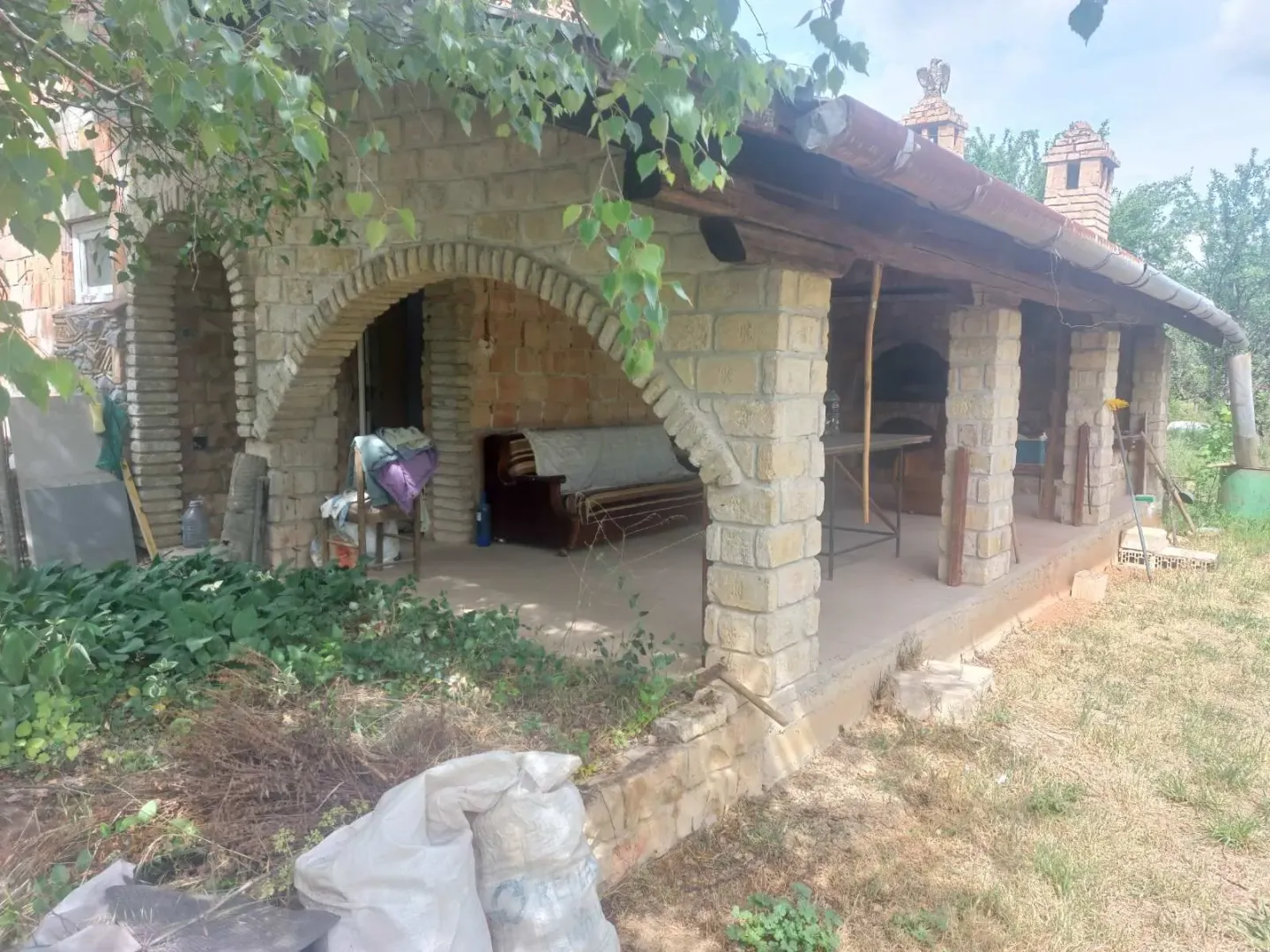 Spoljni dio kuće sa natkrivenom terasom od kamena.