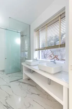 Moderne kupatilo sa dva umivaonika, mermernim podom i staklenom tuš kabinom. - image 16