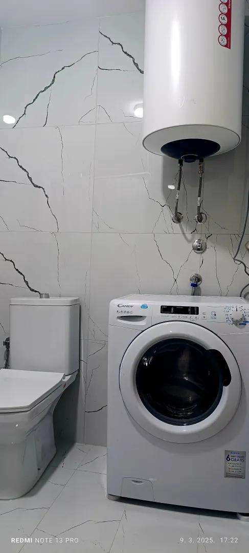 Modernly equipped bathroom with a washing machine and water heater.