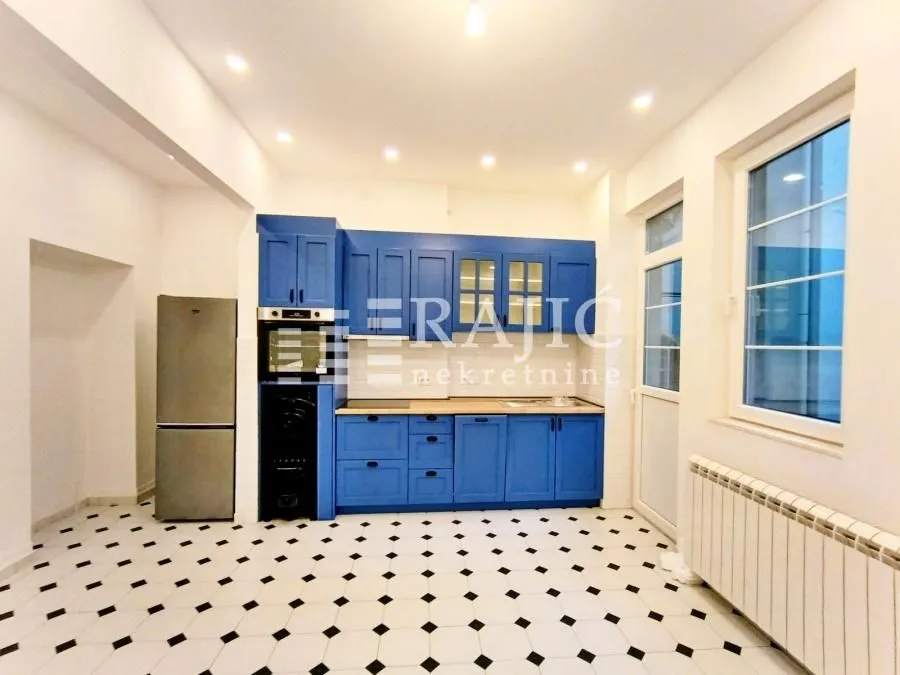 Spacious kitchen with blue cabinetry and black-and-white ceramic floor tiles.