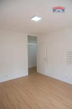 Prazna soba sa belim zidovima, laminatom na podu i otvorenim vratima. - image 3