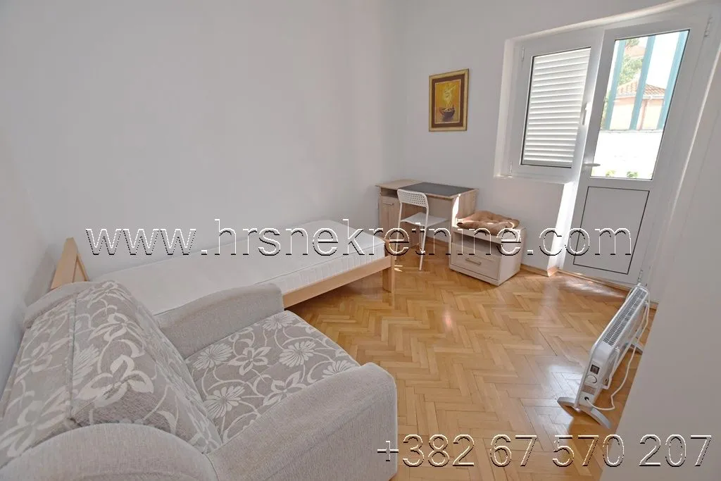 Furnished bedroom with a bed, armchair, and desk.